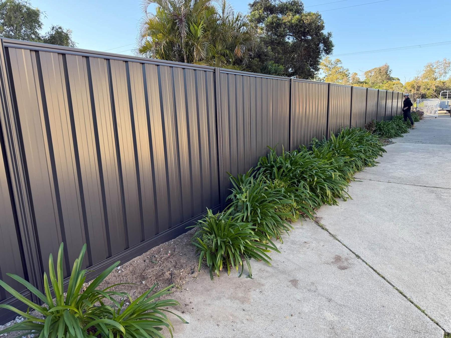 Dark Colorbond boundary fence along a garden bed