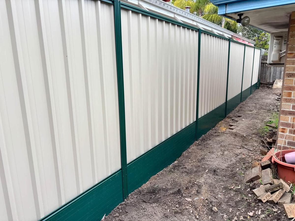 Cream Colorbond fence with contrasting green posts and plinths