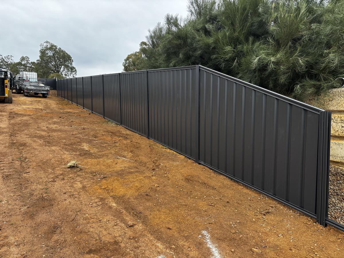 Raked Colorbond fence stepping up to a retaining wall