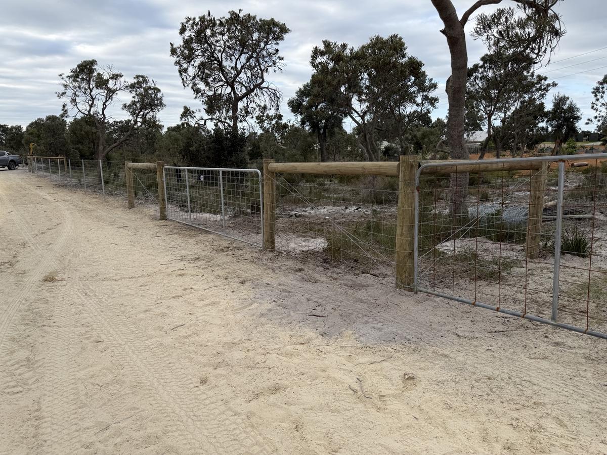 Rural mesh fence with timber strainers and farm gates